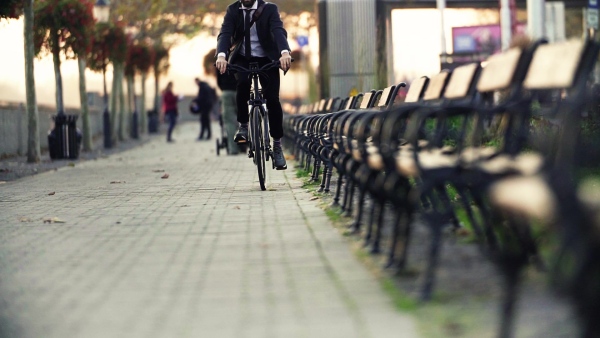 A midsection of businessman commuter traveling home from work in city on a bicycle. Slow motion.