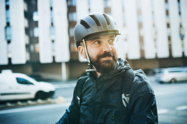 Male courier with bicycle helmet delivering packages in city. Copy space.