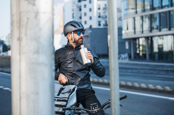 Male hipster courier resting when delivering packages in city. Copy space.