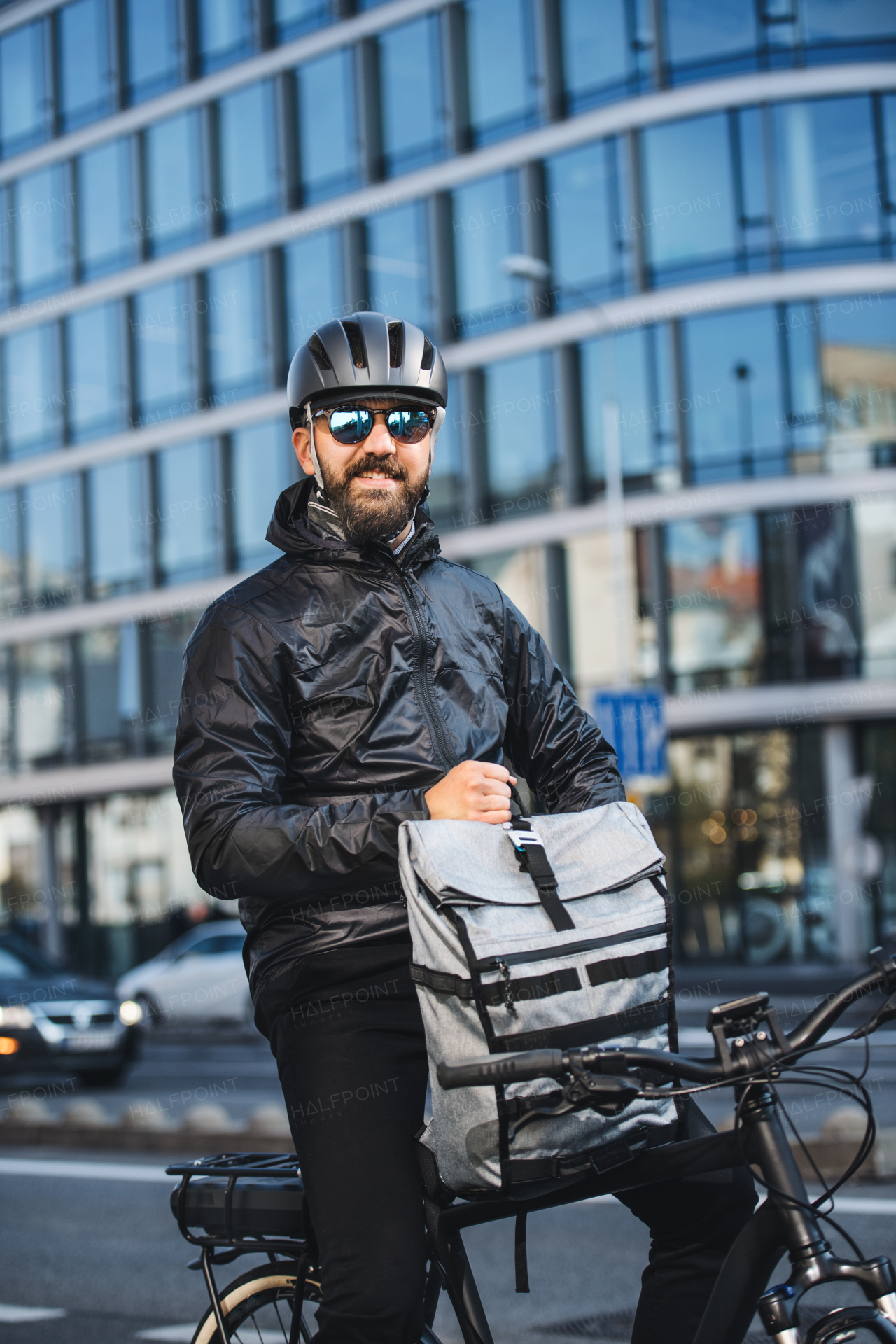 A portrait of male bicycle courier with backpack delivering packages in city.