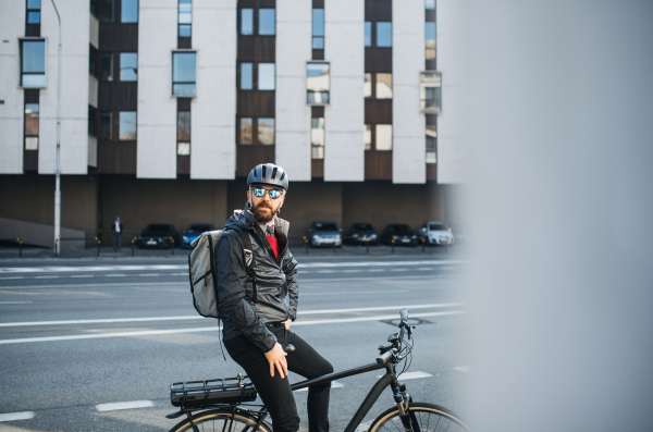 A portrait of male bicycle courier with backpack delivering packages in city.