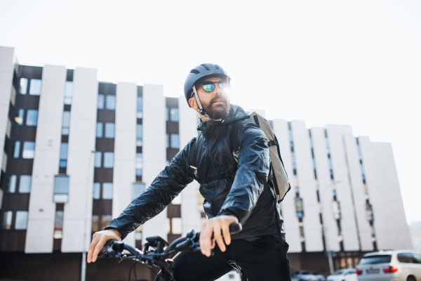 Male courier with bicycle and sunglasses delivering packages in city. Copy space.