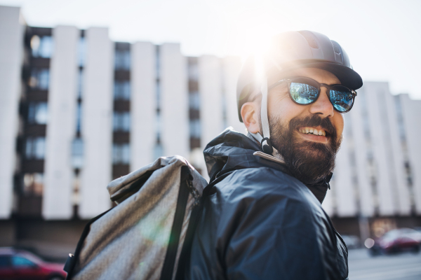 Male courier with sunglasses delivering packages in city. Copy space.