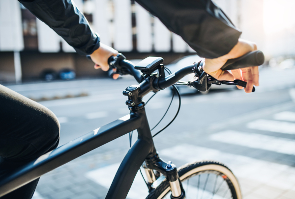 A midsection of businessman commuter with electric bicycle traveling to work in city. A close-up.