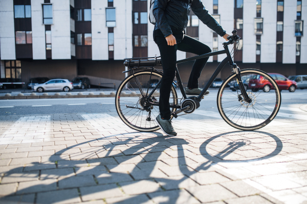 Midsection of unrecognizable male hipster courier with bicycle on a road in city, delivering packages. Copy space.