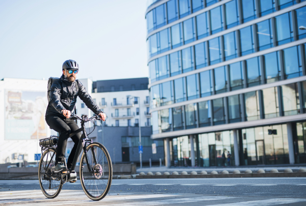 A male bicycle courier with sunglasses cycling in city, delivering packages. Copy space.