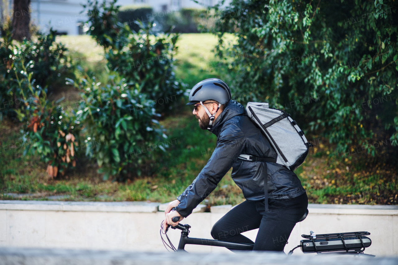 A male bicycle courier cycling in city, delivering packages. Copy space.