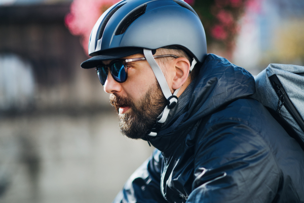 Male hipster courier with bicycle cycling on a road in city, delivering packages.