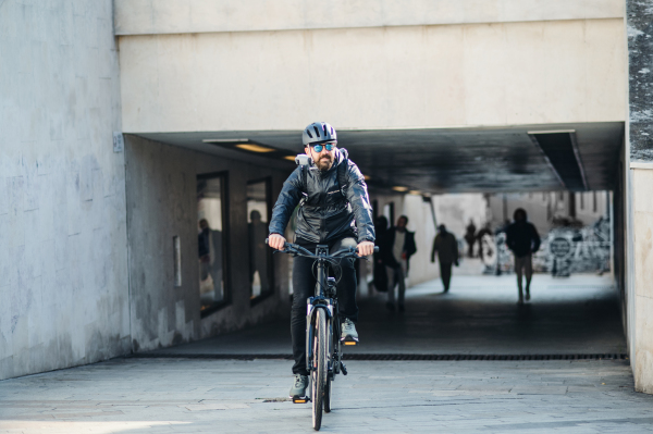 A male bicycle courier cycling in city, delivering packages. Copy space.