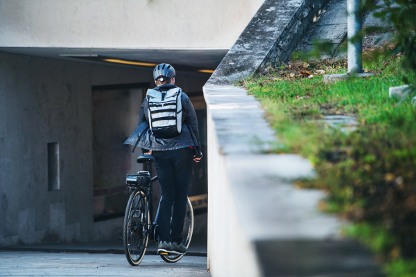 A rear view of male bicycle courier cycling in city, delivering packages. Copy space.