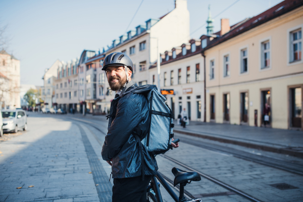 A male courier with backpack delivering packages in city.