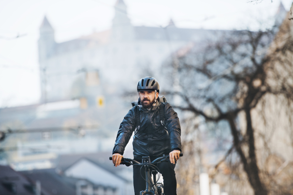 Male hipster courier with bicycle cycling on a road in city, delivering packages. Copy space.