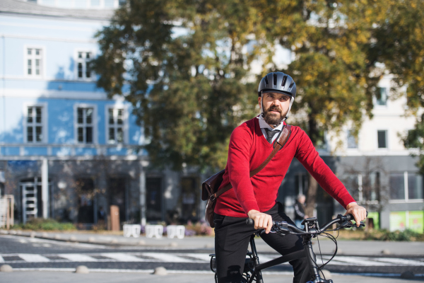 Hipster businessman commuter with electric bicycle traveling to work in city. Copy space.