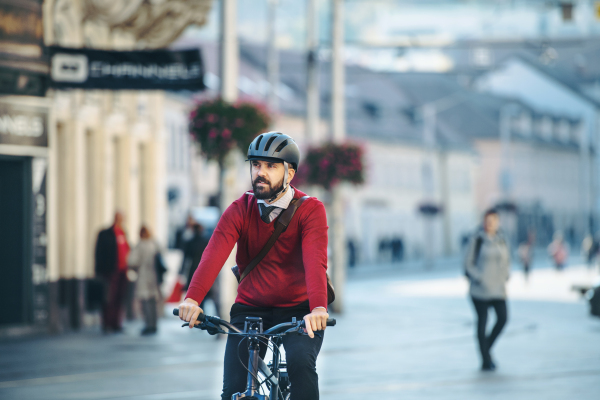 Hipster businessman commuter with electric bicycle traveling to work in city. Copy space.