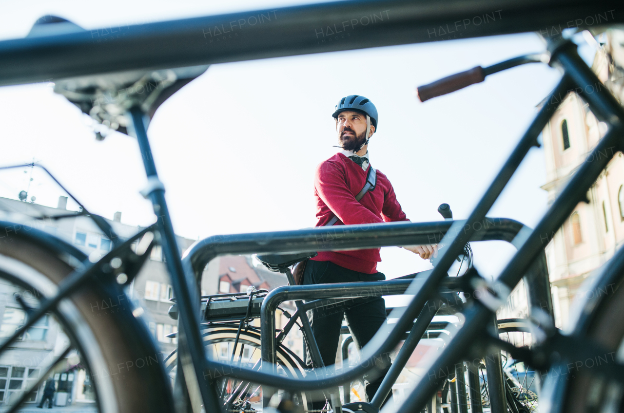 A hipster businessman commuter parking electric bicycle in city when going to work.