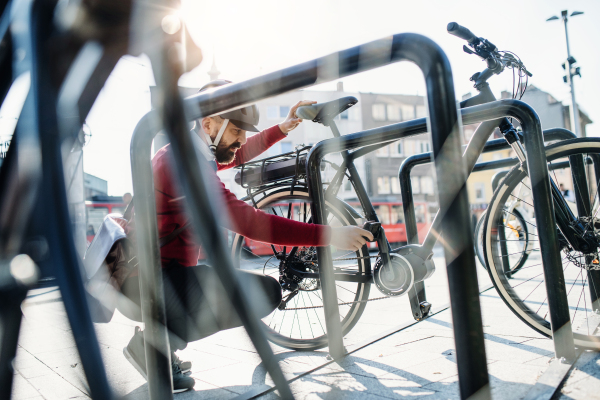 A hipster businessman commuter parking electric bicycle in city when going to work.