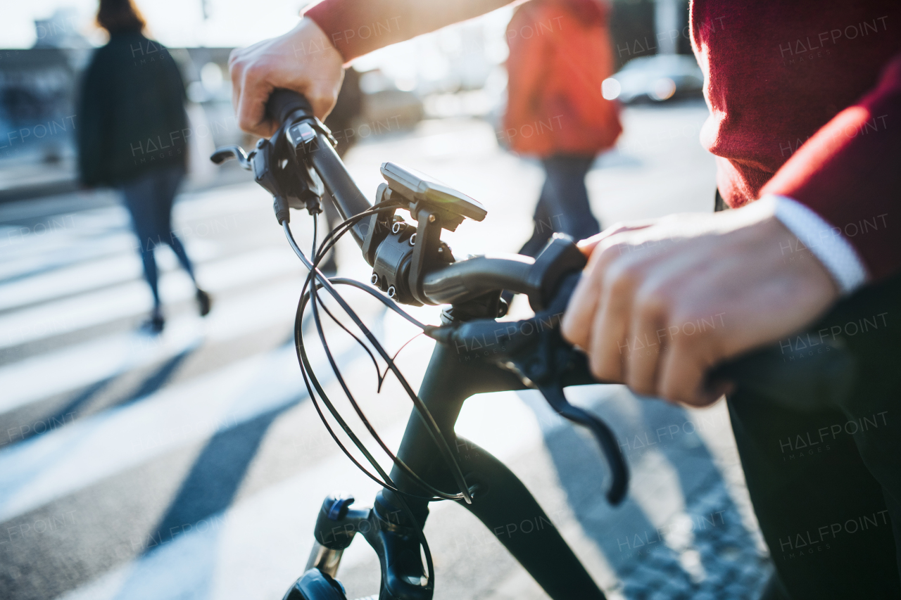 A midsection of businessman commuter with electric bicycle traveling to work in city. A close-up.