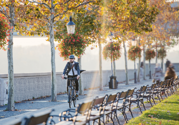 Hipster businessman commuter with bicycle traveling home from work in city at sunset. Copy space.