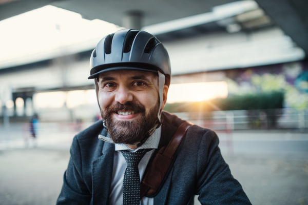 A front view of hipster businessman commuter with bicycle traveling to work in city.