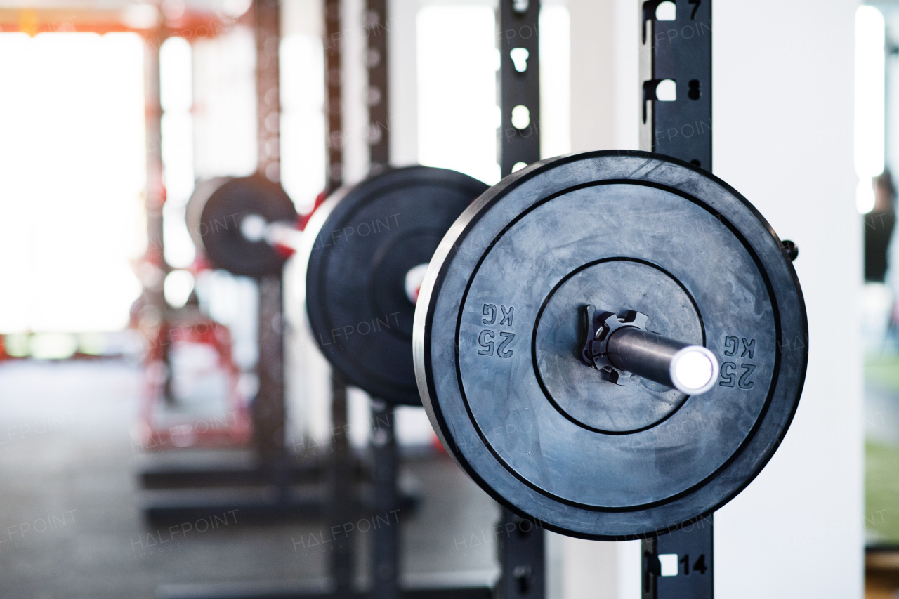 Close up of metal heavy barbell in holder in modern gym. Weight training equipment