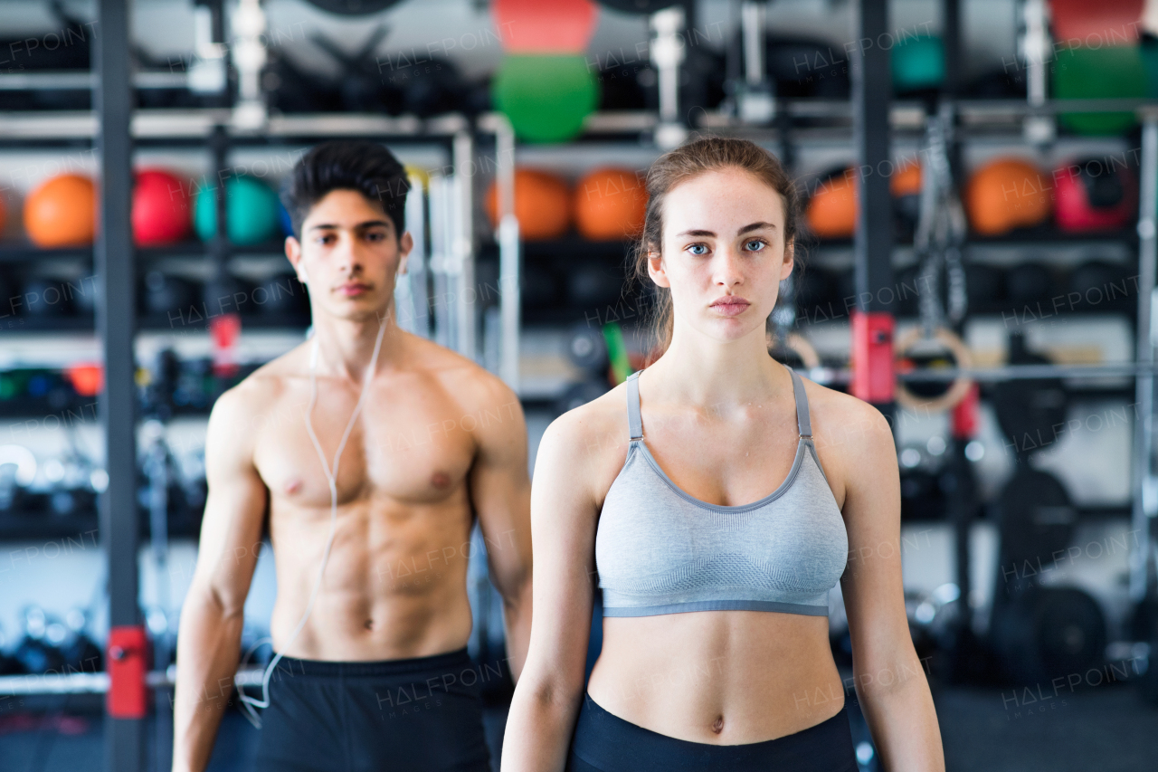 Beautiful young fit couple prepared for exercising in modern gym.