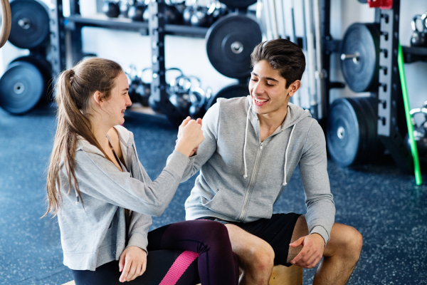 Beautiful young fit couple in modern crossfit gym doing fist pump.