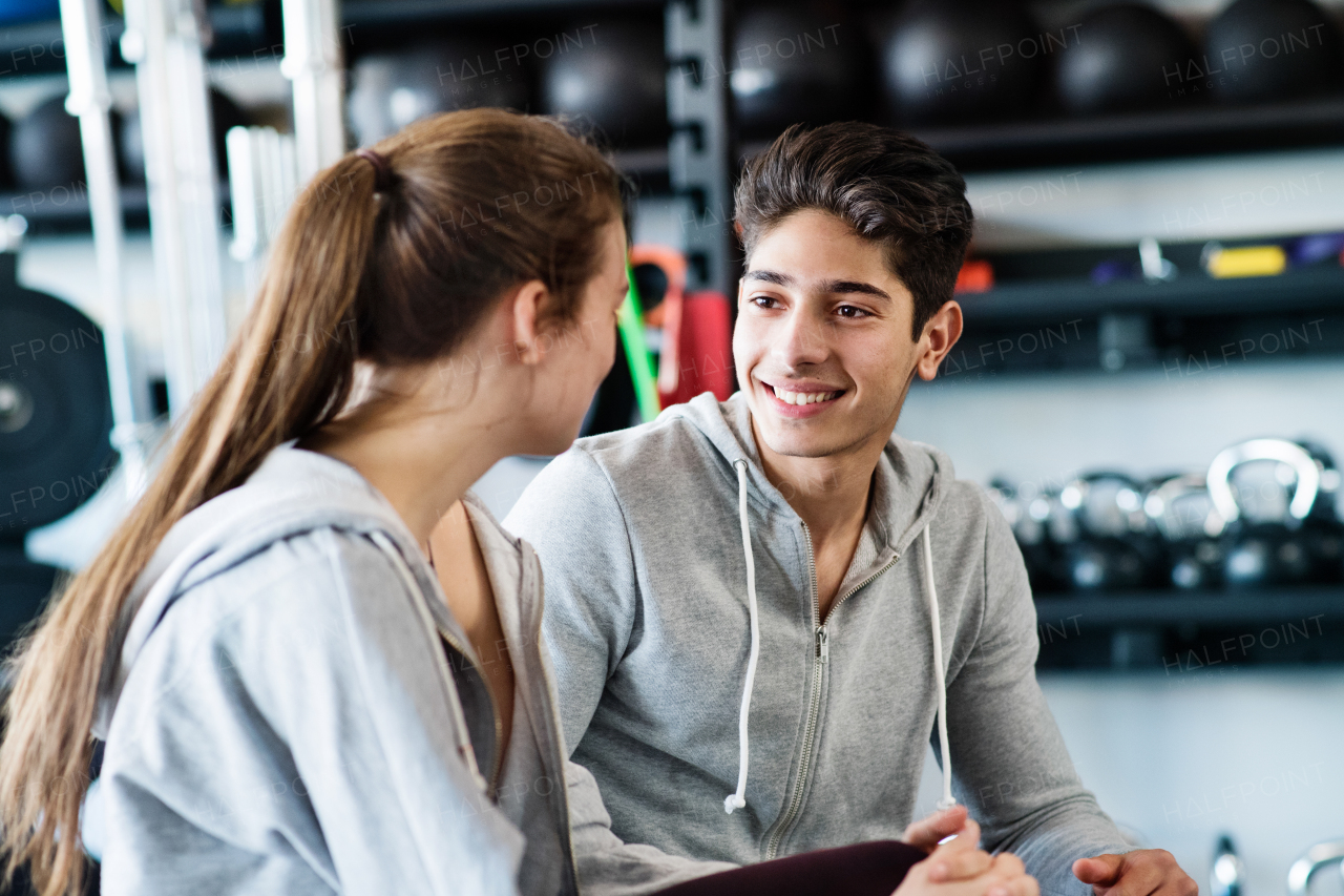 Beautiful young fit couple talking in modern crossfit gym.