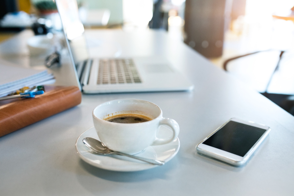 Office desk with coffee cup, smartphone and laptop. The interior of working office space.