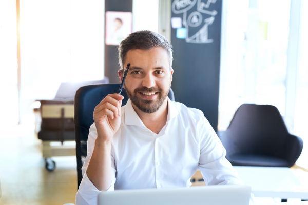 Handsome young businessman in his office, sitting at the desk.