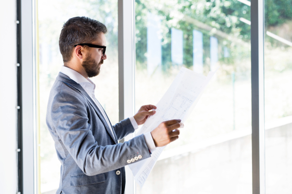 Handsome young businessman in his office studying plans.