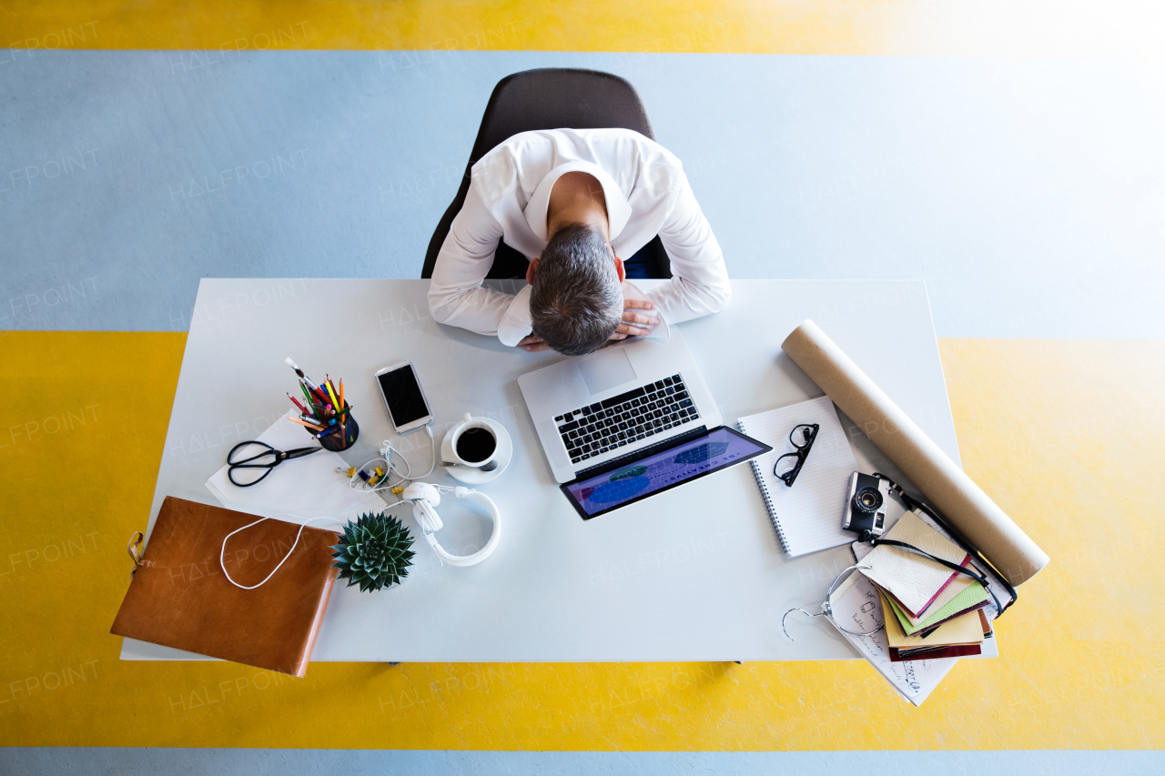 Young hipster businessman in his office, sitting at the desk, having a break and resting.