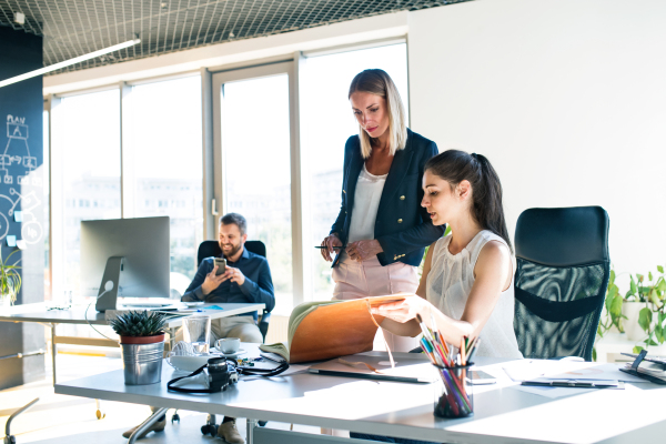 Three attractive young business people in the office working together, consulting a project.