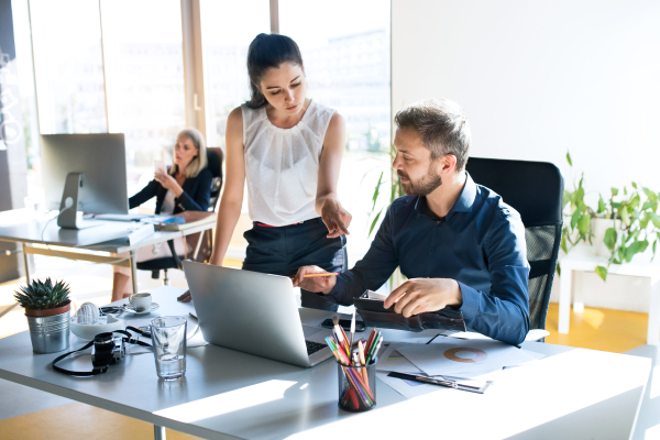 Three business people in the workplace. Two women and man sitting in the office working together.