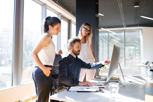 Three business people discussing in the workplace. Two women and man in the office working together.