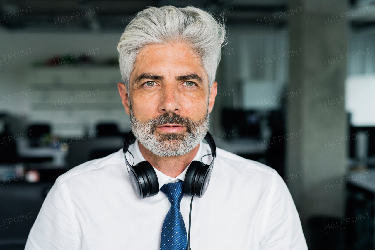 Handsome mature businessman with headphones in the office.