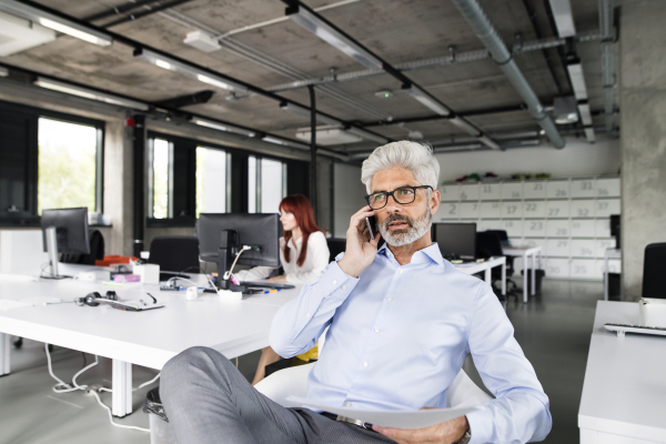 Business people in the office working together. Mature businessman making a phone call.