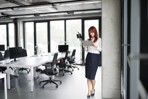 Beautiful young businesswoman with tablet in her office working.