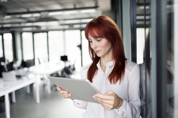 Beautiful young businesswoman with tablet in her office working.