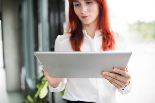 Beautiful young businesswoman with tablet in her office working.