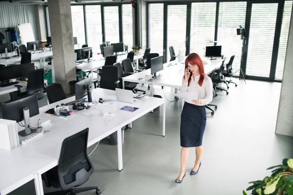 Beautiful young businesswoman with smart phone in her office making a phone call.