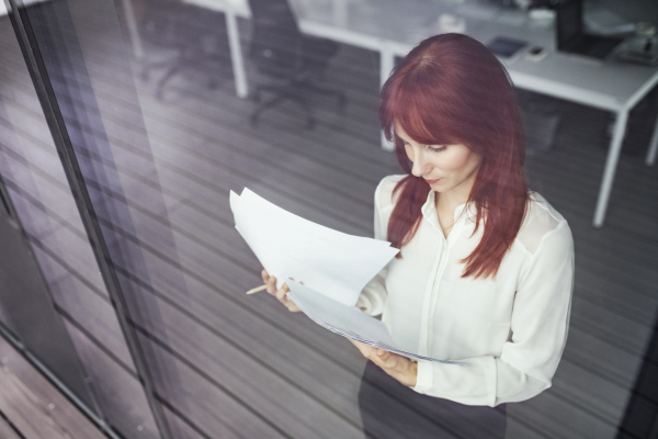 Beautiful young businesswoman working in her office, reading documents.