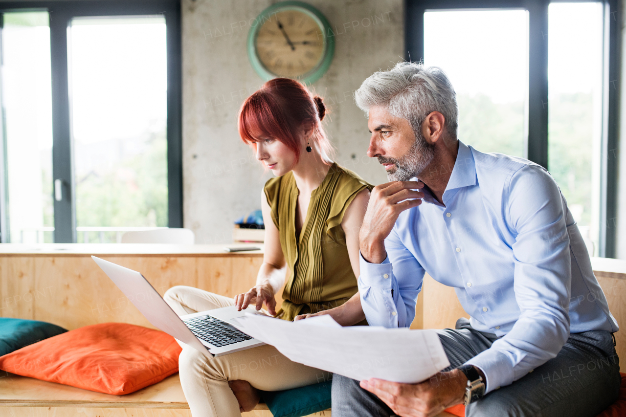 Two business people in workplace. Woman and man in creative office consulting a project together.