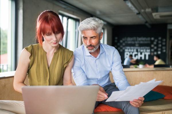 Two business people in workplace. Woman and man in creative office consulting a project together.