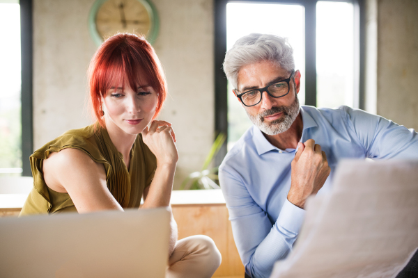 Two business people in workplace. Woman and man in creative office consulting a project together.