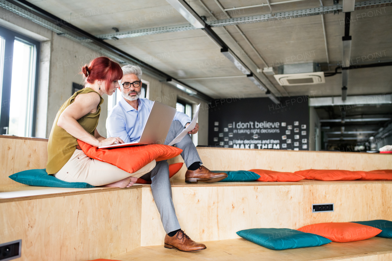 Two business people in workplace. Woman and man in creative office consulting a project together.