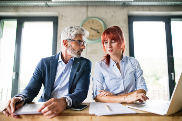 Two business people in workplace. Woman and man in creative office consulting a project together.