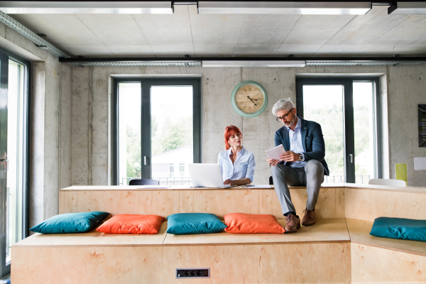 Two business people in workplace. Woman and man in creative office consulting a project together.