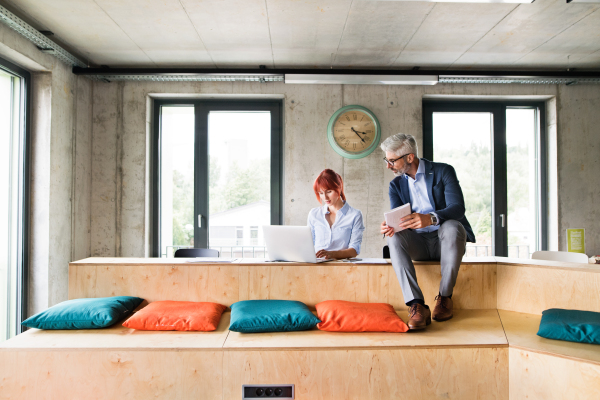 Two business people in workplace. Woman and man in creative office consulting a project together.