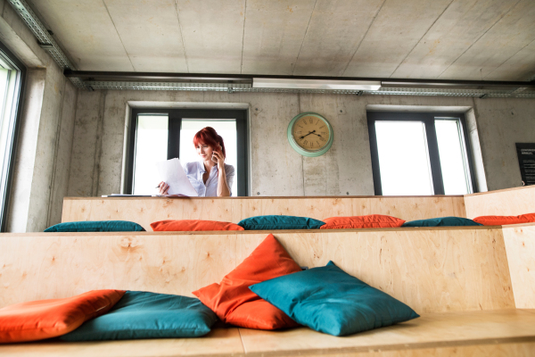 Mature businesswoman working at the desk in creative office, reading documents.