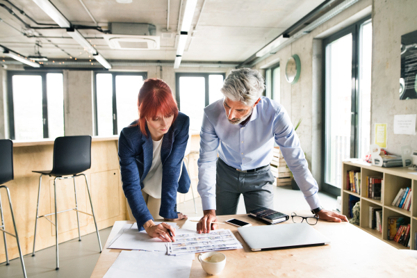 Two business people in creative office discussing a project together.